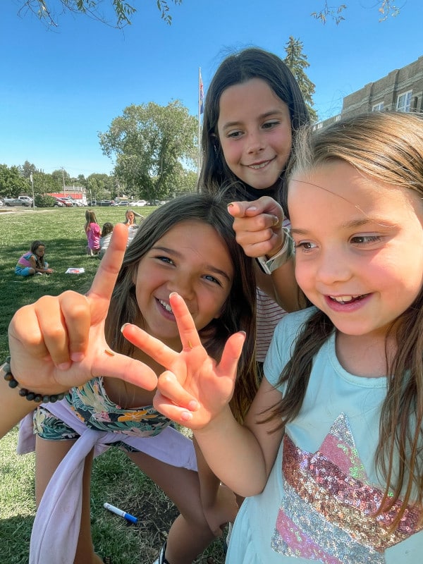 A group of girls holding up hand symbols in a park