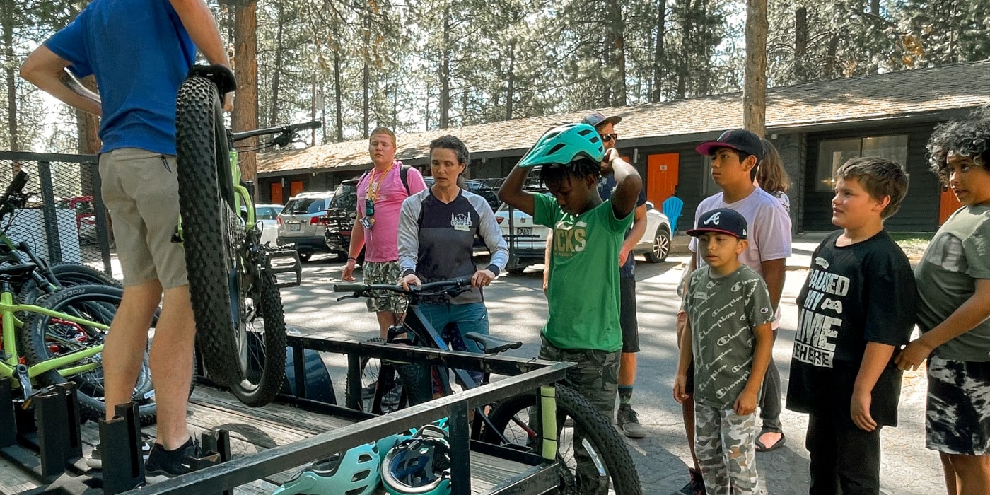 A group of kids listening to a man give a talk about mountain biking
