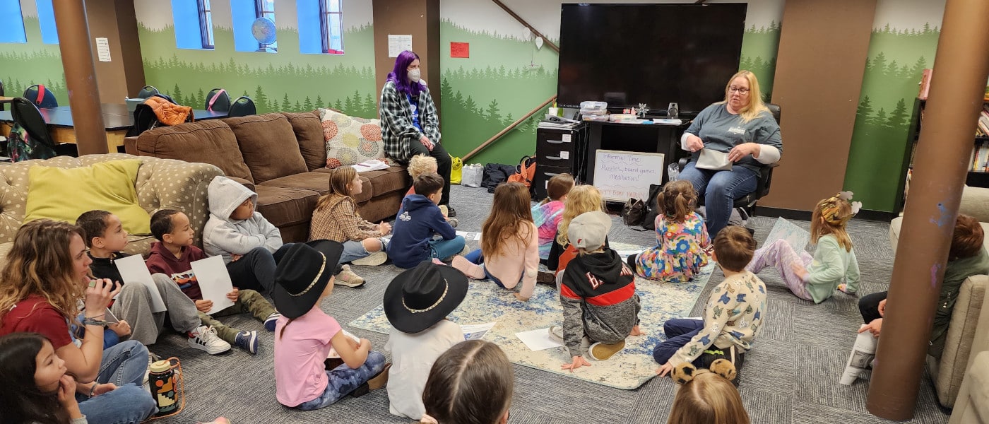 A group of kids sitting in a classroom listening to a teacher talk