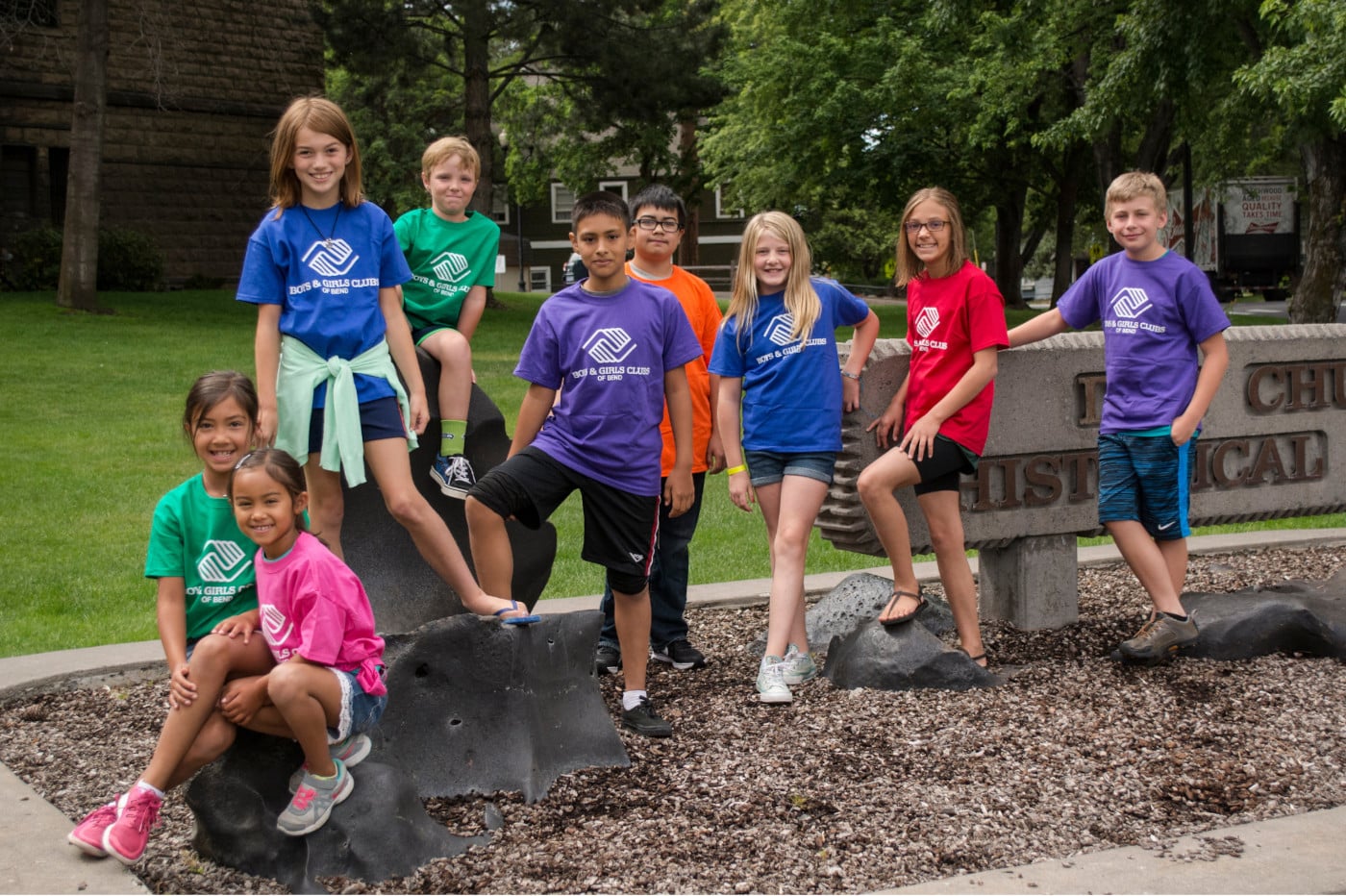 A group of kids at a park wearing girls and boy clubs shirts