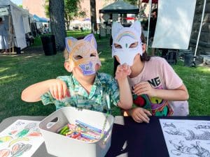Two kids outside drawing and wearing hand colored face masks