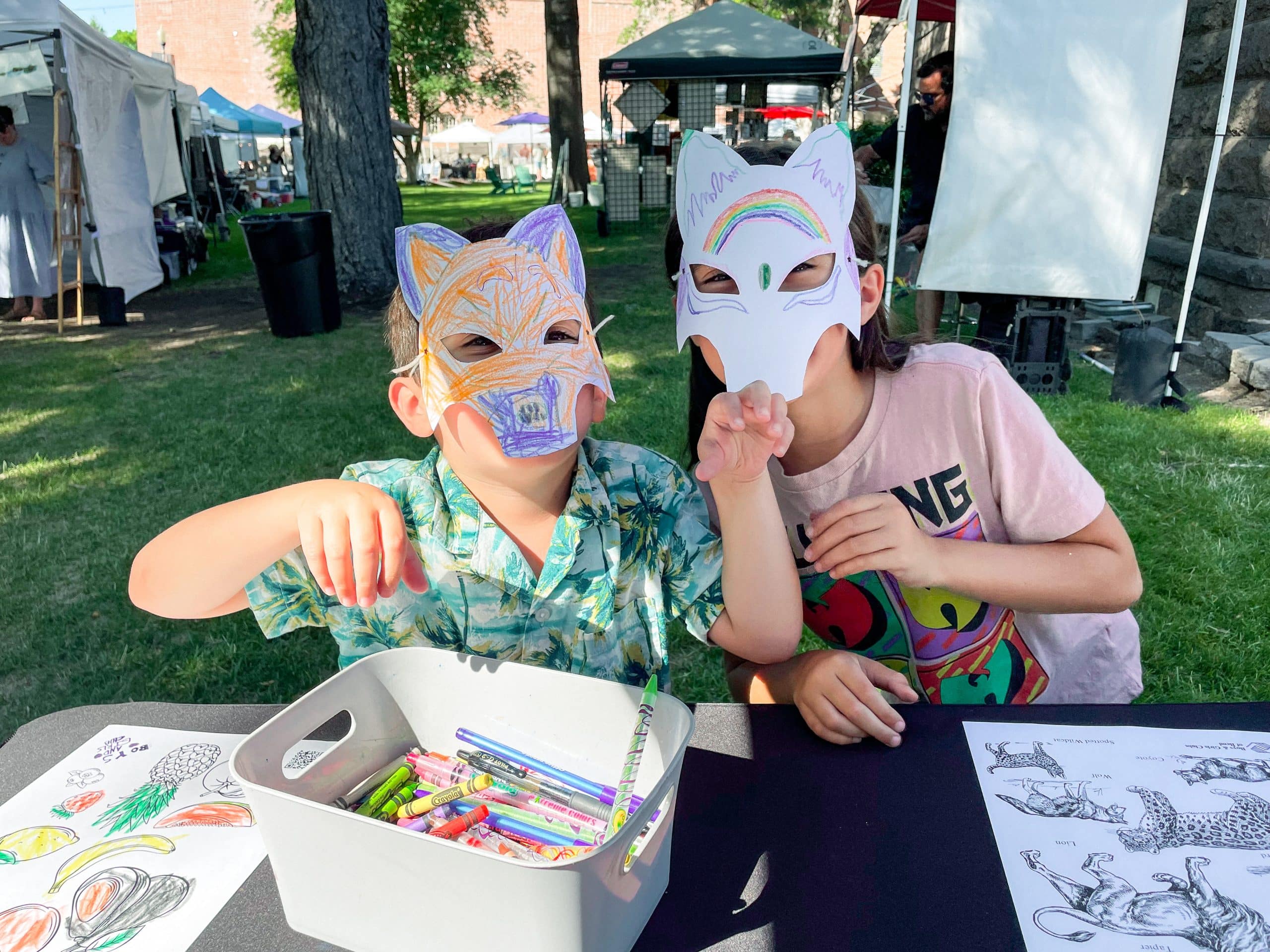 Two kids wearing hand colored animal masks at an event