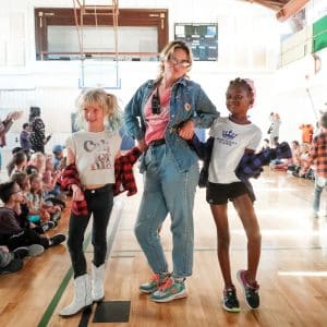 A volunteer and two kids walking down doing a fashion show