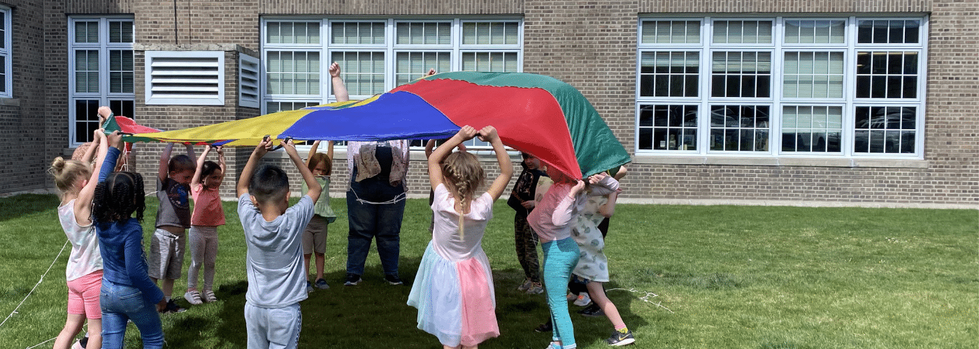 A group of kids playing with a multicolor parachute