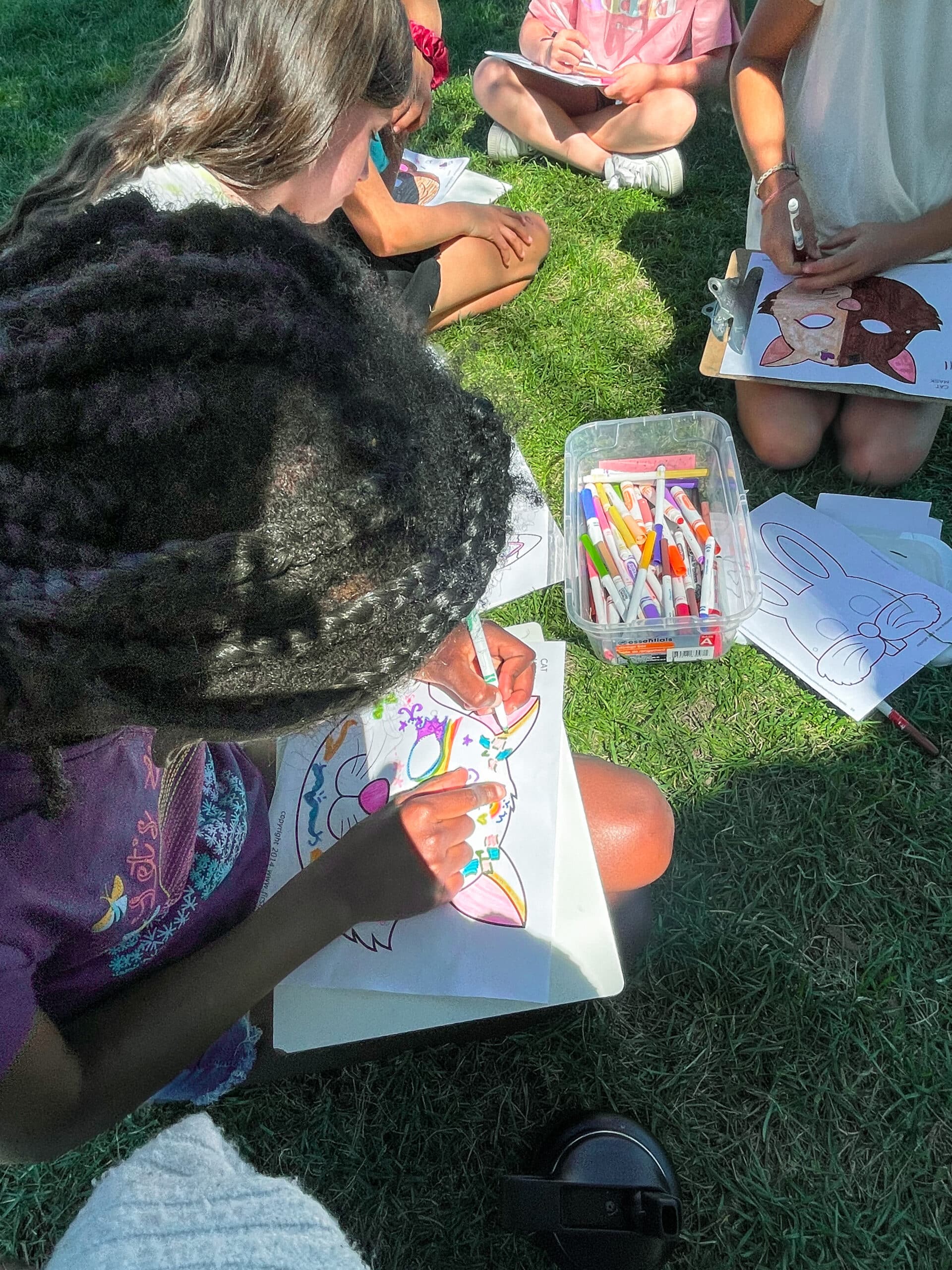 kids coloring in the grass from behind