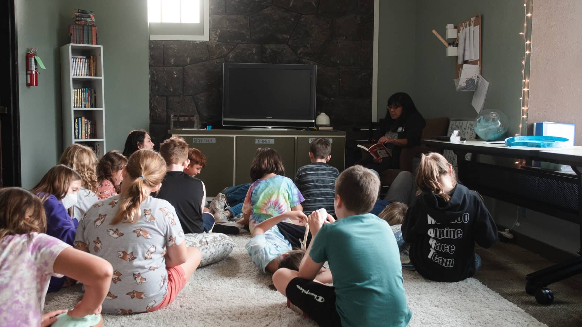A group of kids sitting in front of a TV with a teacher
