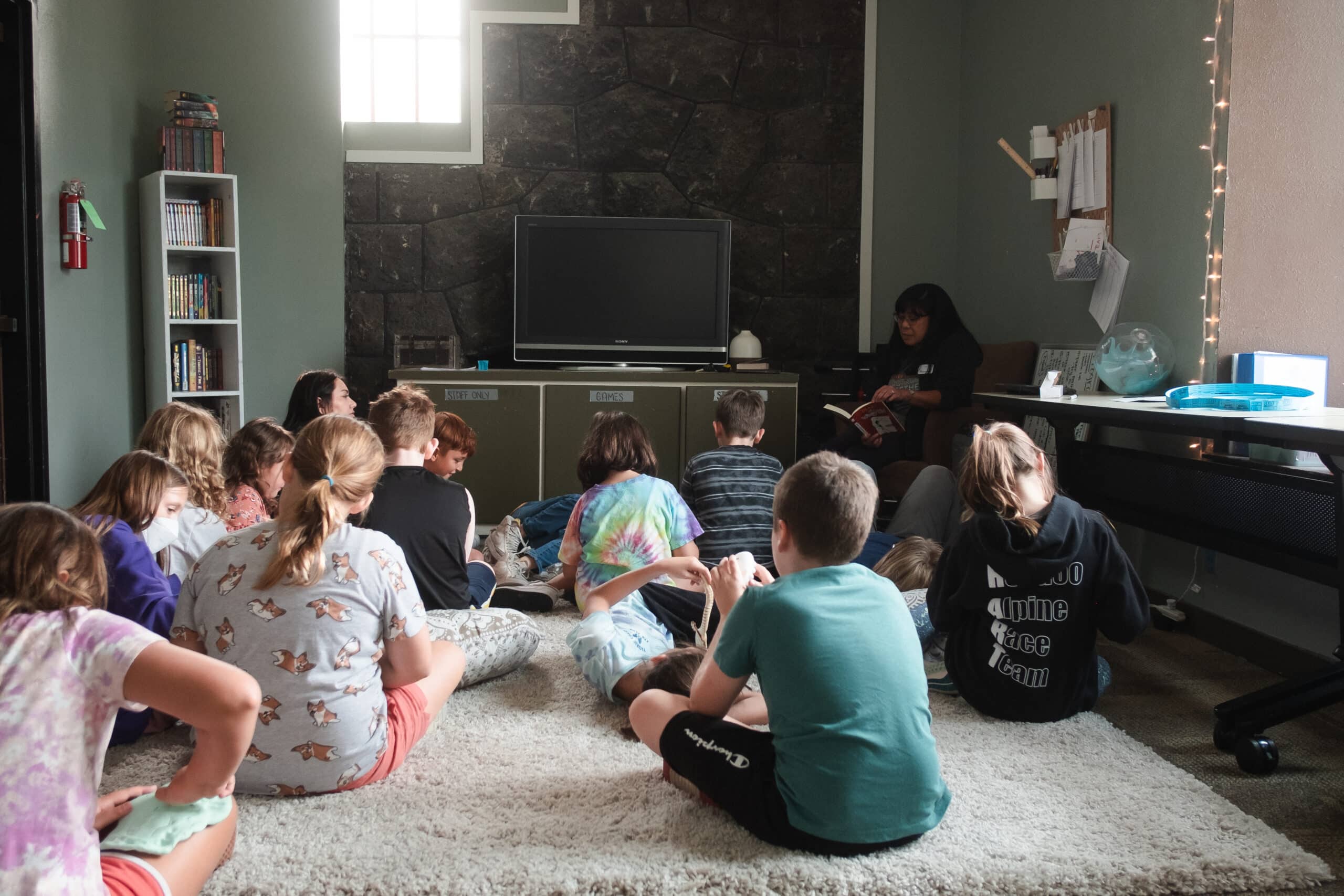 A group of kids sitting in front of a TV with a teacher
