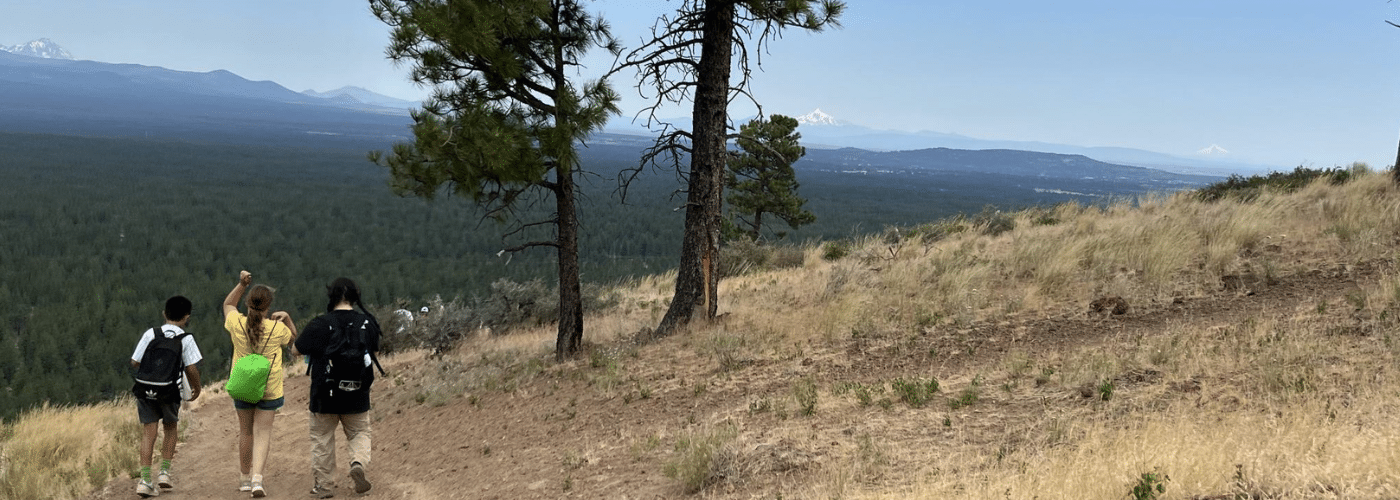 A group of people hiking up a dessert type mountain.