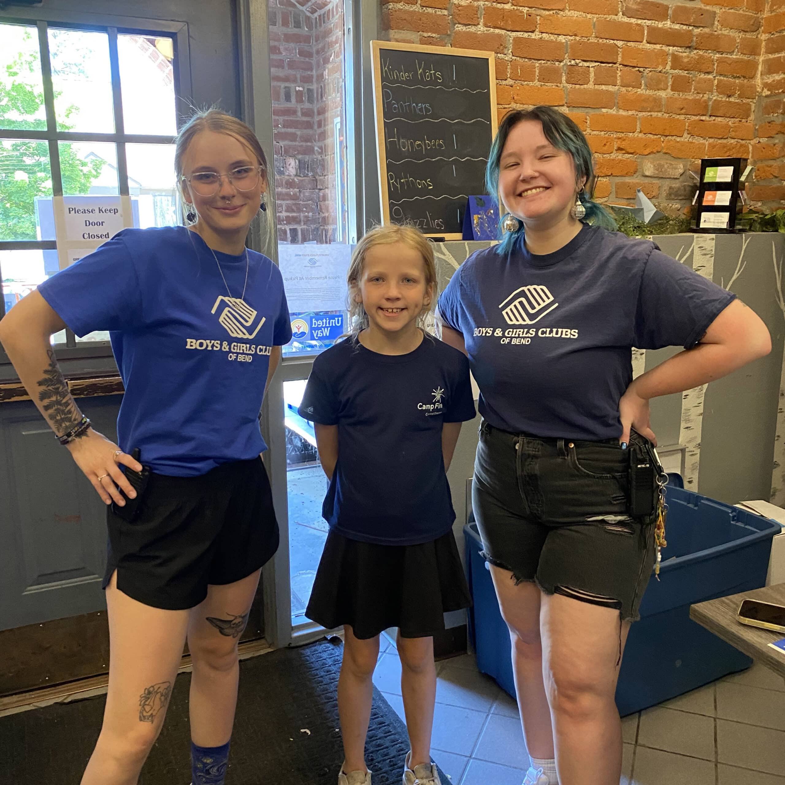 a group of three women with boys & girls club shirts posing for a picture