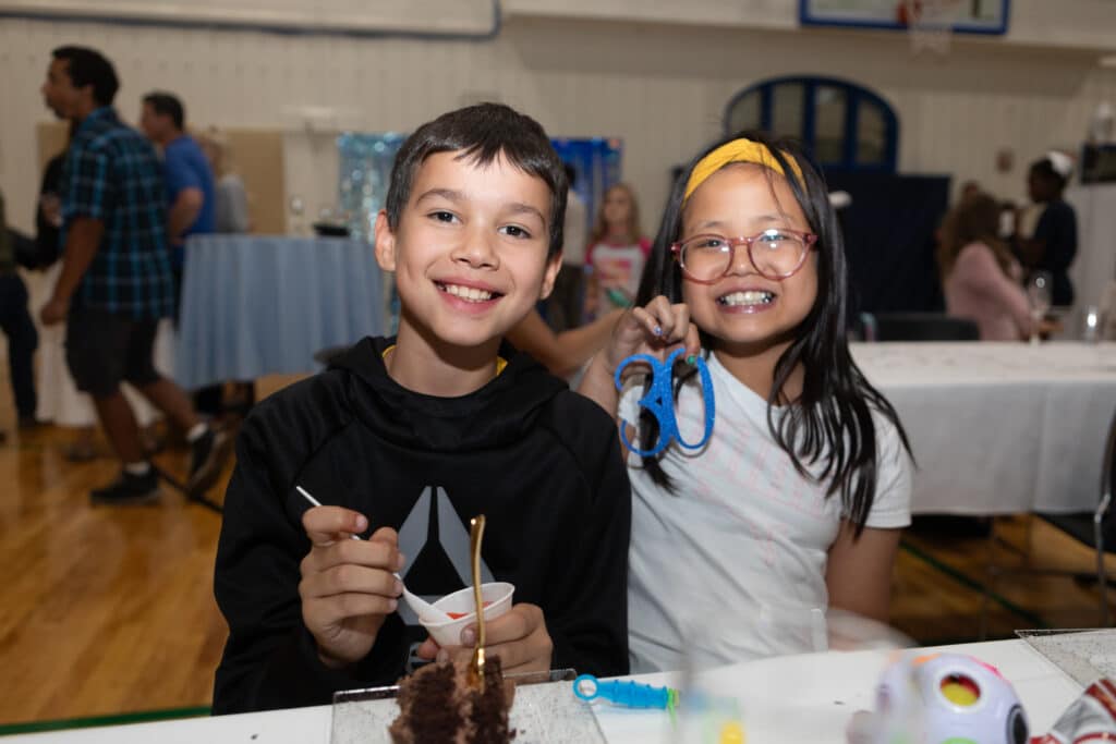 a boy and girl smiling at the camera while doing an activity