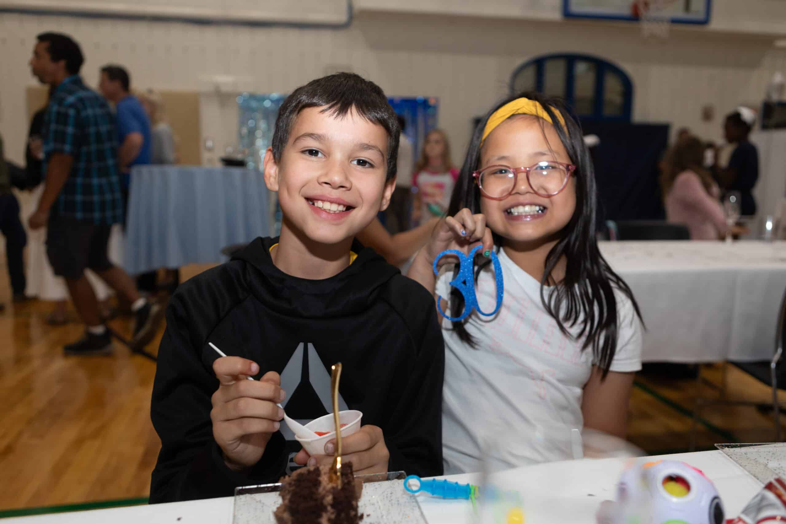 A young girl and boy at a party in the school gym