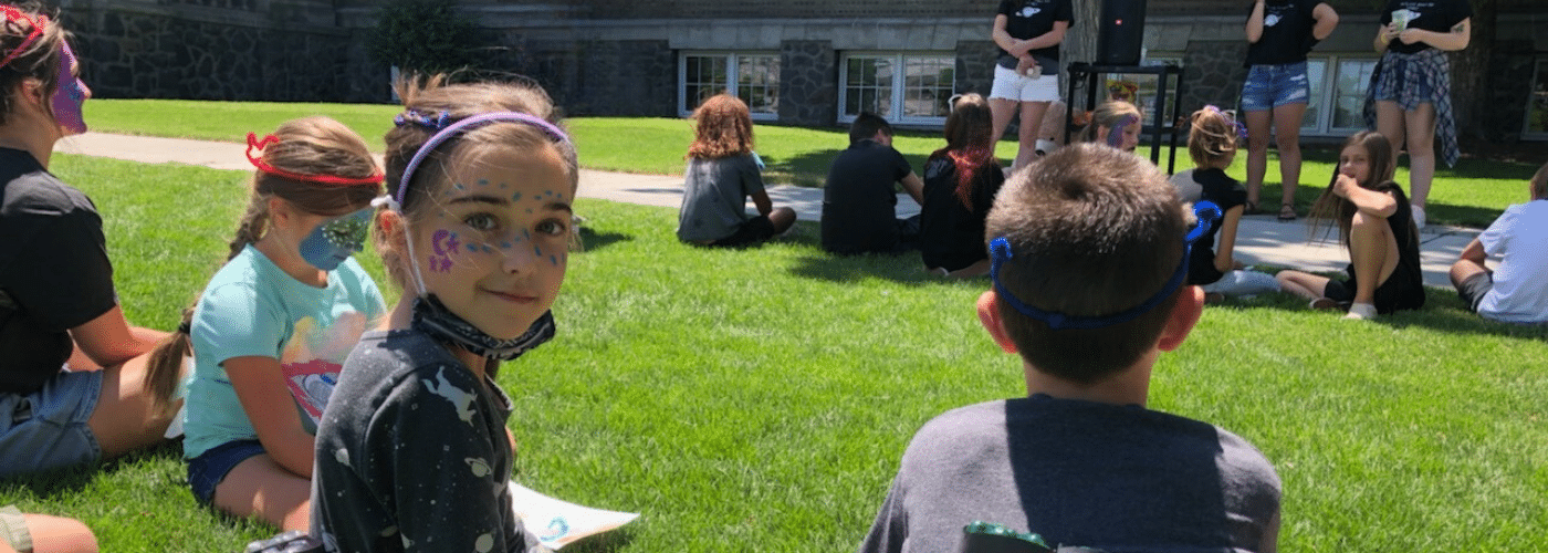 A group of kids on a grass field sitting down